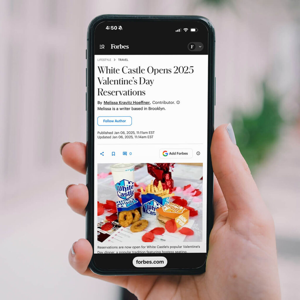 Image of a hand holding a mobile phone with an article about White Castle on the screen
